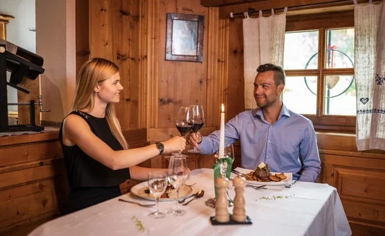 Couple toasting with red wine in cozy wooden interior restaurant