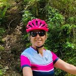 Frau mit Helm neben Mountainbike auf Waldweg