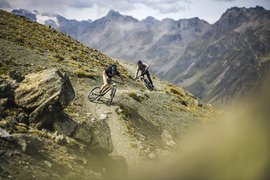 Zwei Mountainbiker fahren einen Bergpfad in den Alpen hinunter