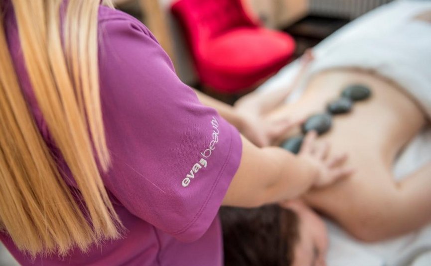 BIKE BREAK (7 Nächte) Frau erhält Hot-Stone-Massage auf dem Rücken im Wellnessbereich