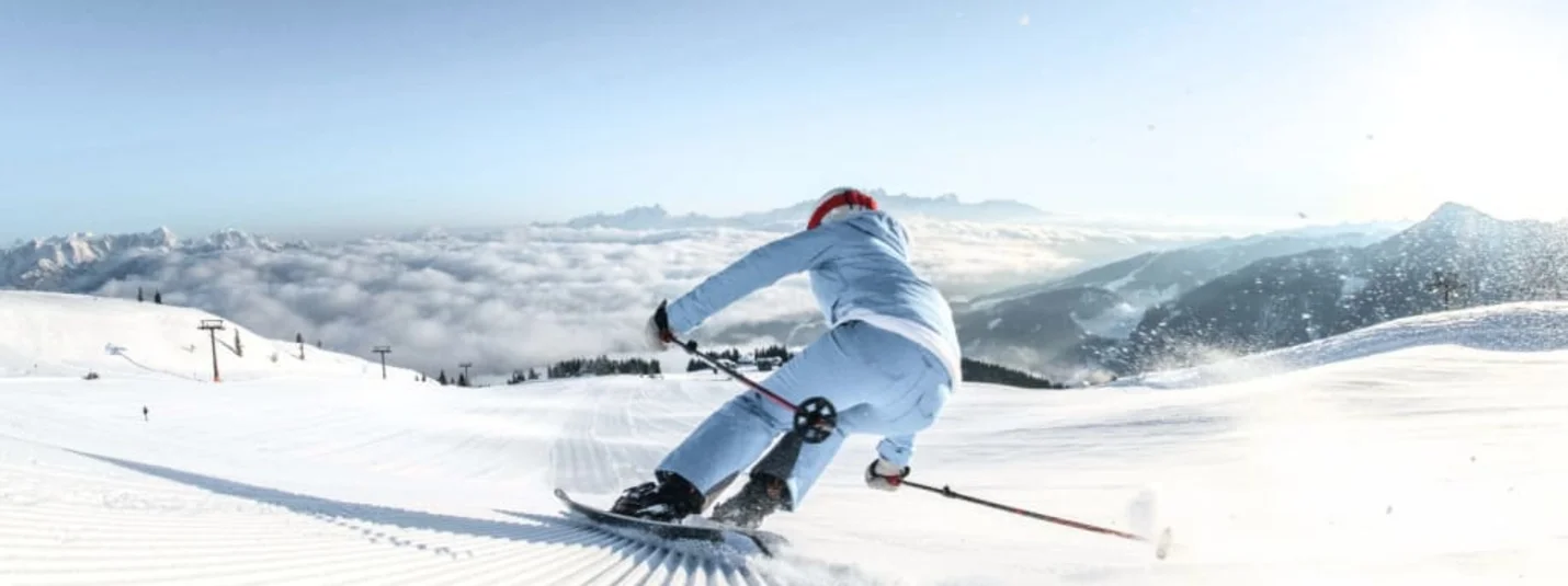Skier descending a freshly groomed slope on a sunny mountain day