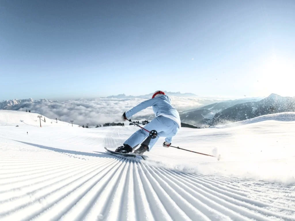 Skifahrer fährt eine frisch präparierte Piste an einem sonnigen Bergtag hinunter
