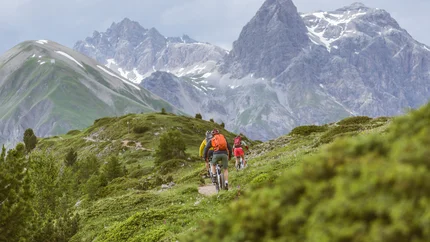 Fietsers op een bergpad met hoge bergen op de achtergrond