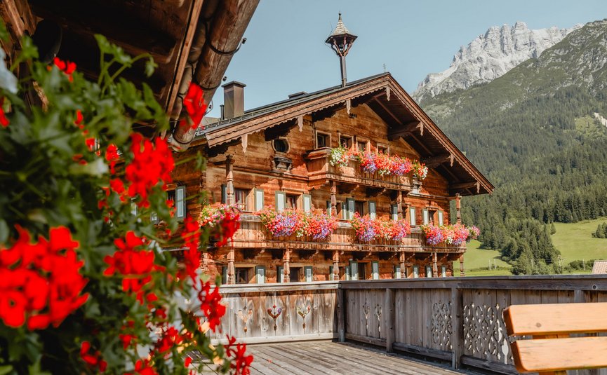 Puradies © Jeppe Zoffmann Holzhaus mit bunten Blumenbalkonen und Berg im Hintergrund