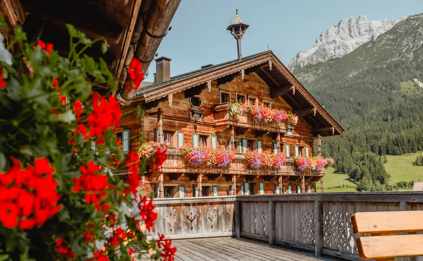 Holzhaus mit bunten Blumenbalkonen und Berg im Hintergrund