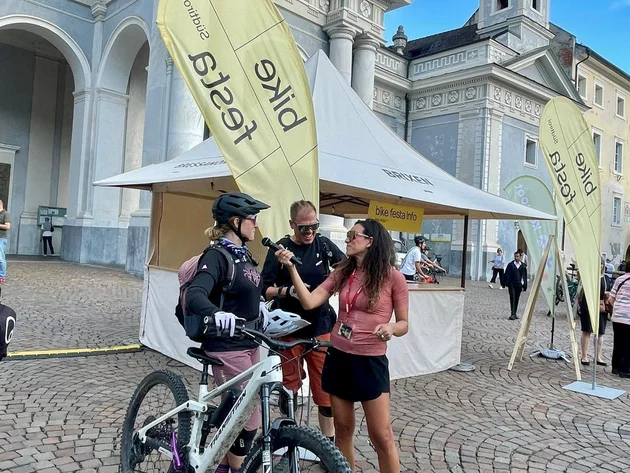 Das war die bike festa Südtirol in Brixen © Max Messner - Interview auf der bike festa Südtirol 2026 Mountainbiker mit Fahrrad spricht mit einer Frau vor einem historischen Gebäude mit Eventzelt