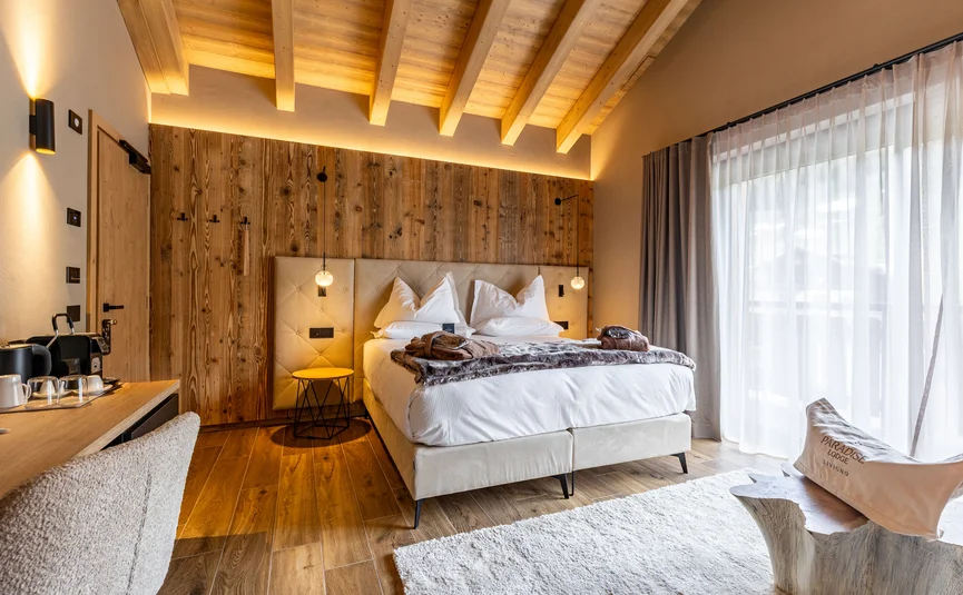 Gemütlicher Hotelzimmer mit Holzakzenten, Bett und großen Fenstern