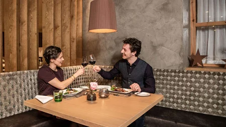 Koppel die proost met rode wijn in modern restaurant