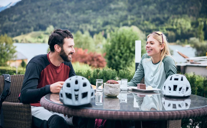 Zwei Radfahrer genießen Kuchen im Freien mit Bergblick