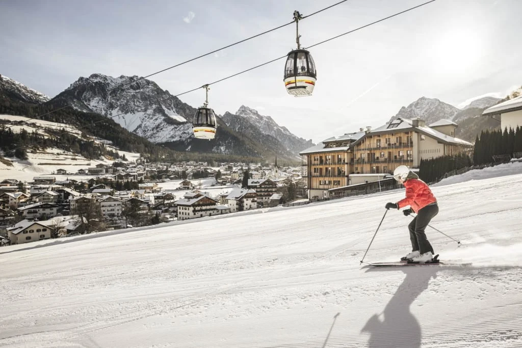 Skier in red jacket skiing near cable cars in snowy mountain village