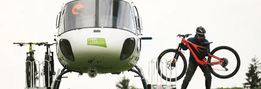Hubschrauber mit Fahrrädern auf einer Wiese, eine Person trägt ein Fahrrad