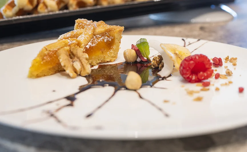 Stück Apfelkuchen mit Nüssen und Beeren auf Teller mit Schokosauce dekoriert