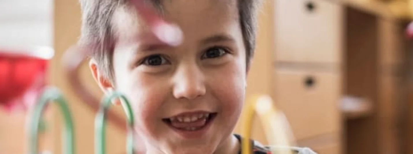 Glimlachende jongen speelt met een kleurrijk draadspel
