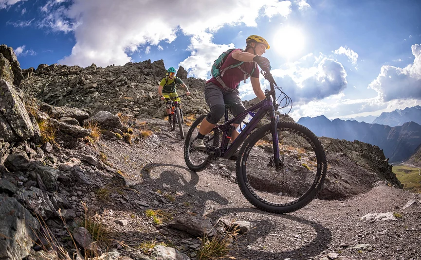 Zwei Mountainbiker fahren auf felsigem Bergpfad bei sonnigem Wetter