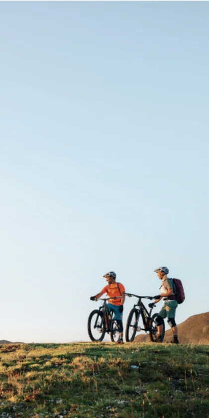 Zwei Radfahrer mit Mountainbikes auf einem Hügel bei klarem Himmel