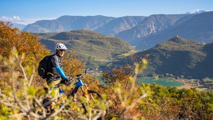 Mountainbiker mit Helm auf einem Hügel mit Berg- und Seeblick