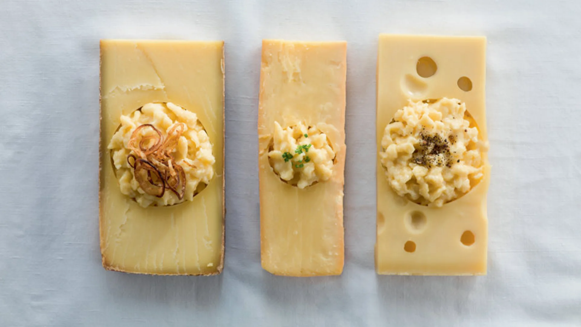 Drei Käsesorten mit Portionen Käsespätzle und Garnitur