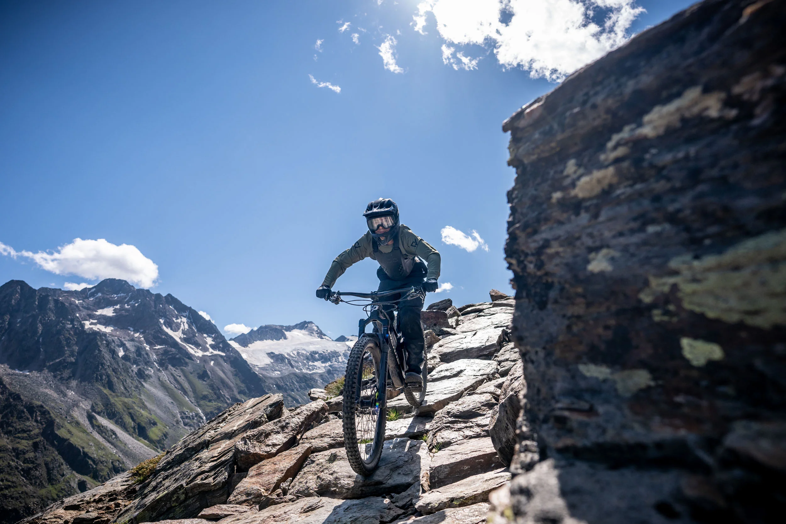 Mountainbiker fährt auf felsigem Bergpfad bei klarem Himmel