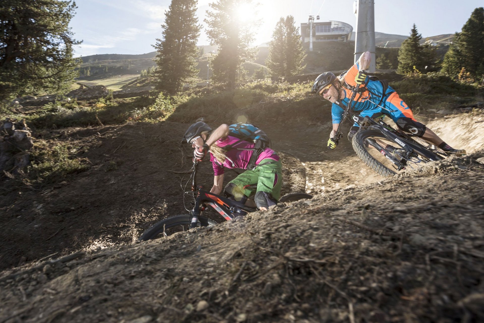 Zwei Mountainbiker fahren eine kurvige Strecke im Gelände bei Sonnenschein