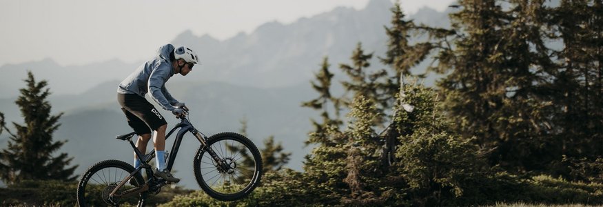 Mountainbiker springt over pad in bergachtig bosgebied