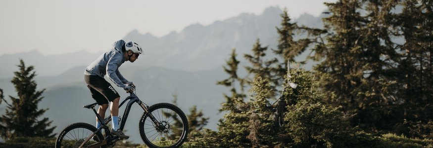 Mountainbiker springt over pad in bergachtig bosgebied