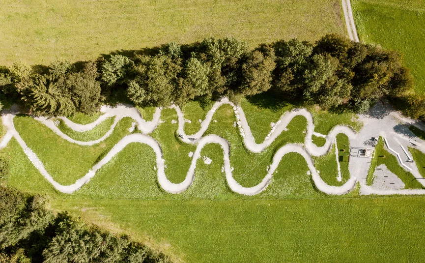 Aerial view of a winding bike path through a green meadow
