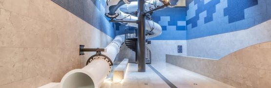 Modern indoor water slide area with white tube slides and blue walls