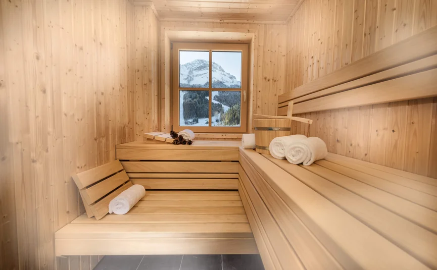 Binnen sauna met houten banken, handdoeken en uitzicht op besneeuwde berg