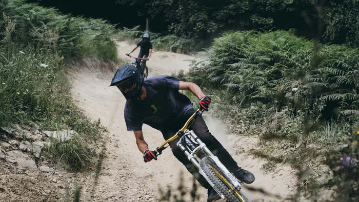Mountainbiker fährt rasant auf staubigem Waldweg