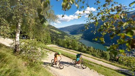 Twee mountainbikers op bergpad met uitzicht op vallei en meer
