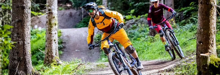 Ready to ride: Das ist neu in Österreichs größter Bike-Region © Klemens König Zwei Mountainbiker fahren auf einem Waldweg, einer in orange, einer in rot