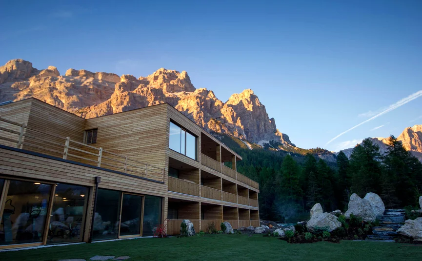 Modern wooden building with forested mountains at sunset