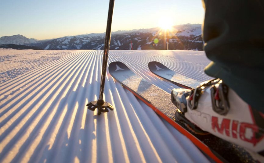 SKI OPENING Skieën op vers geprepareerde piste bij zonsondergang in de bergen