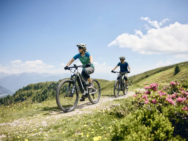 Twee mensen fietsen met e-mountainbikes op een bergpad bij zonnig weer