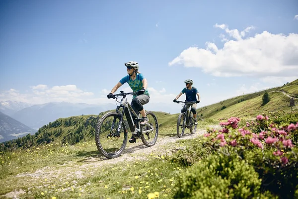 Twee mensen fietsen met e-mountainbikes op een bergpad bij zonnig weer