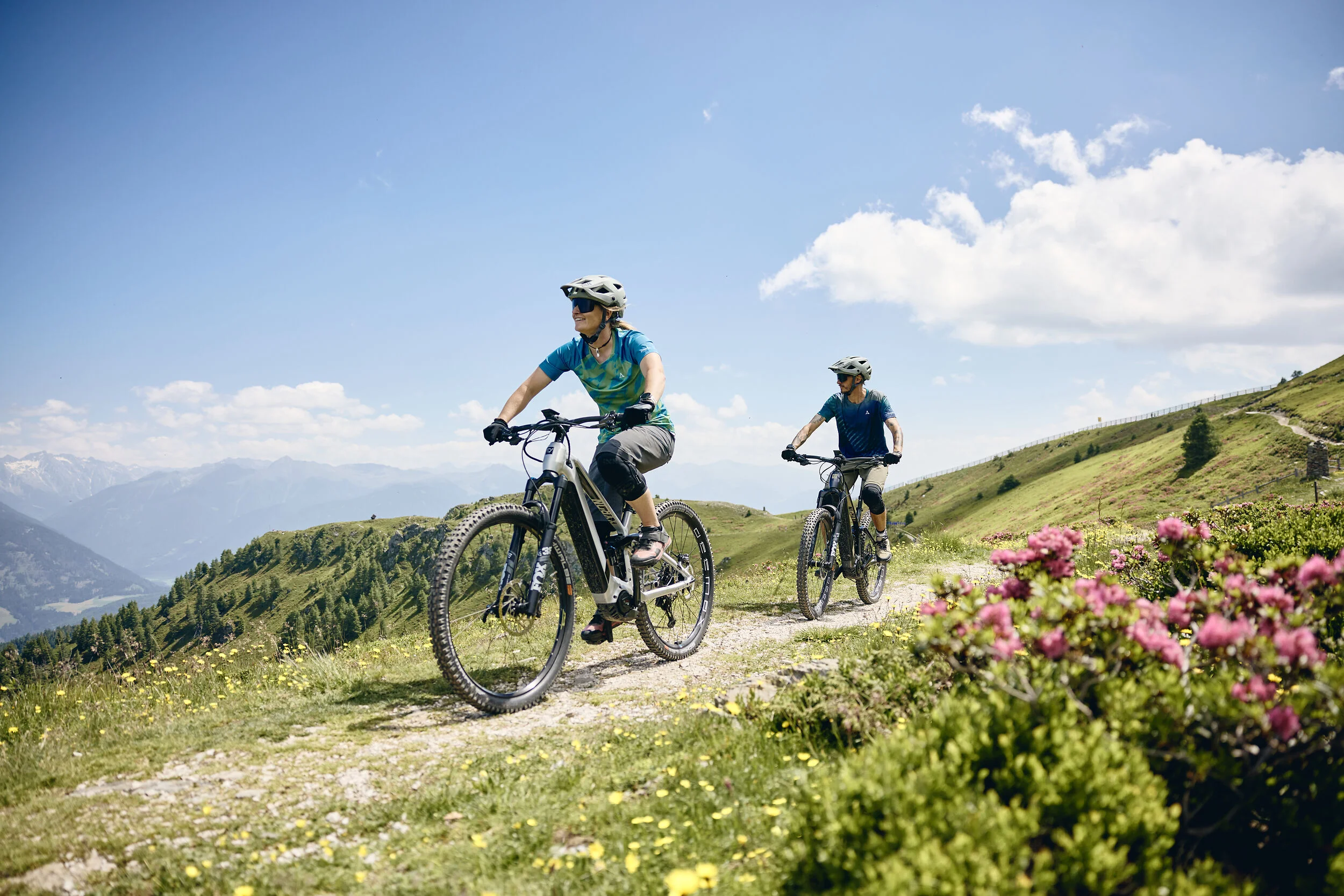 Destinations © Tobias Köhler Two people riding e-mountain bikes on a mountain trail on a sunny day