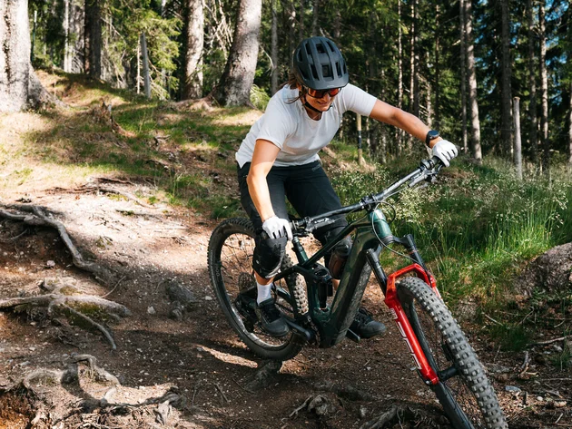 Mit Martina & Flo zum Mountainbiken im LifeSport Hotel Hechenmoos © Martina Wunderle / Flo Distl Frau fährt Mountainbike auf einem Waldweg mit Wurzeln und Steinen