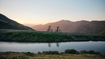 Zum ersten Mal hier © Tobias Köhler Zwei Mountainbiker fahren bei Sonnenuntergang auf einem Bergweg neben einem See