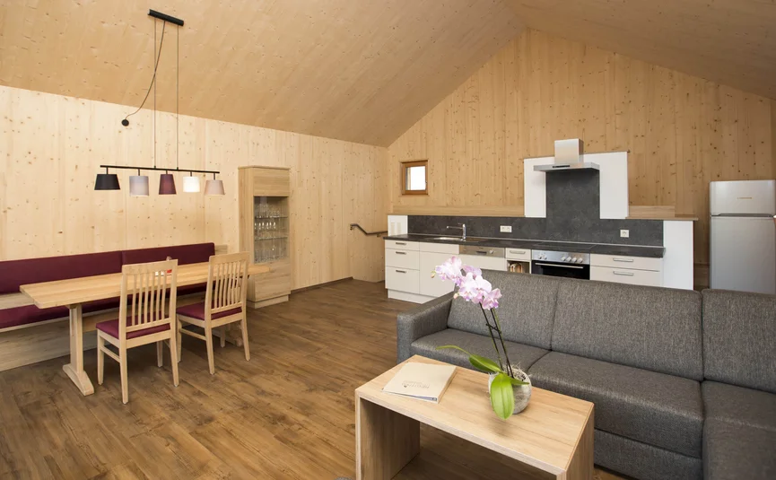 Moderner Wohn- und Küchenbereich mit Holzmobiliar und grauer Couch