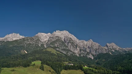 Uitzicht op groene heuvels en ruige bergtoppen onder een heldere lucht