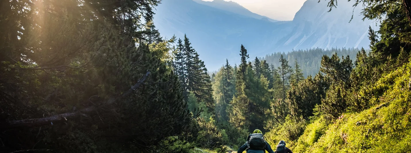 FROM SCHÖNRUH OVER THE THÖRLEN TO LAKE EIBSEE © Norman Bielig Two mountain bikers riding on a forest trail in the mountains during sunlight