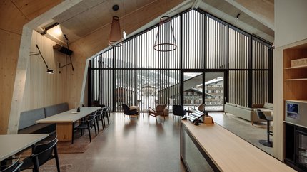 Modernes Wohnzimmer mit großen Fenstern und Stühlen vor Schnee draußen