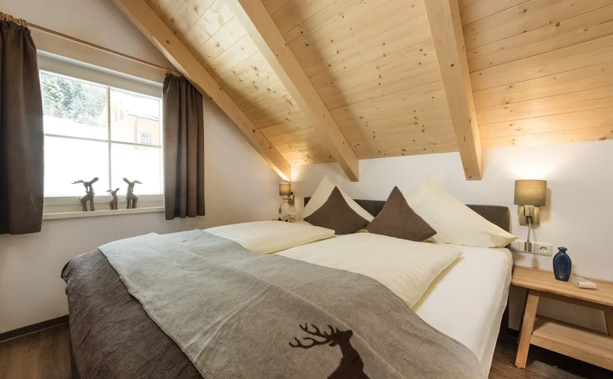 Gezellige slaapkamer met houten balkenplafond en decoratief hertenmotief