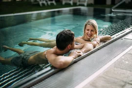 Couple relaxing and chatting in an outdoor pool by the edge