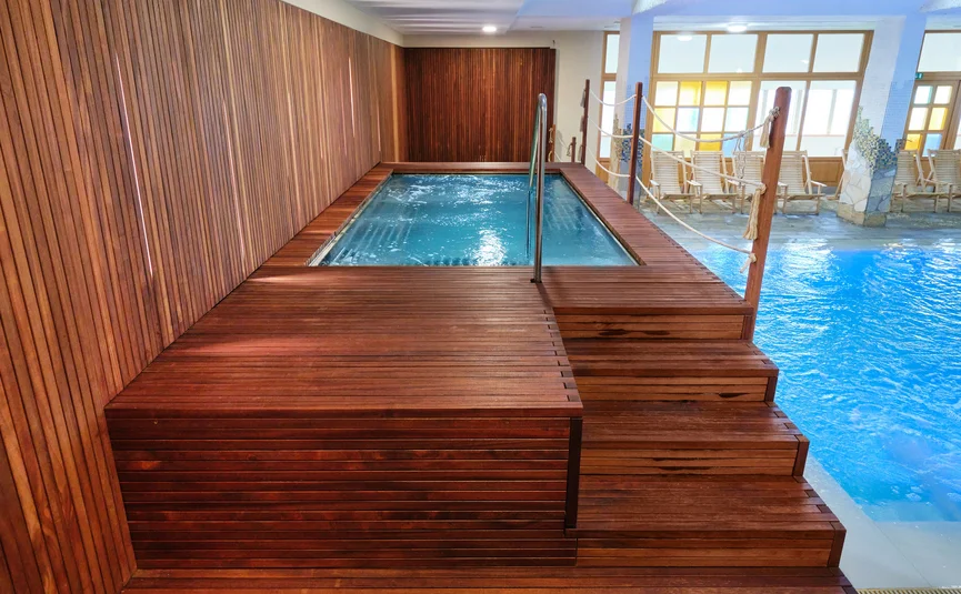 Binnenjacuzzi en zwembad met houten wandbekleding en ligstoelen