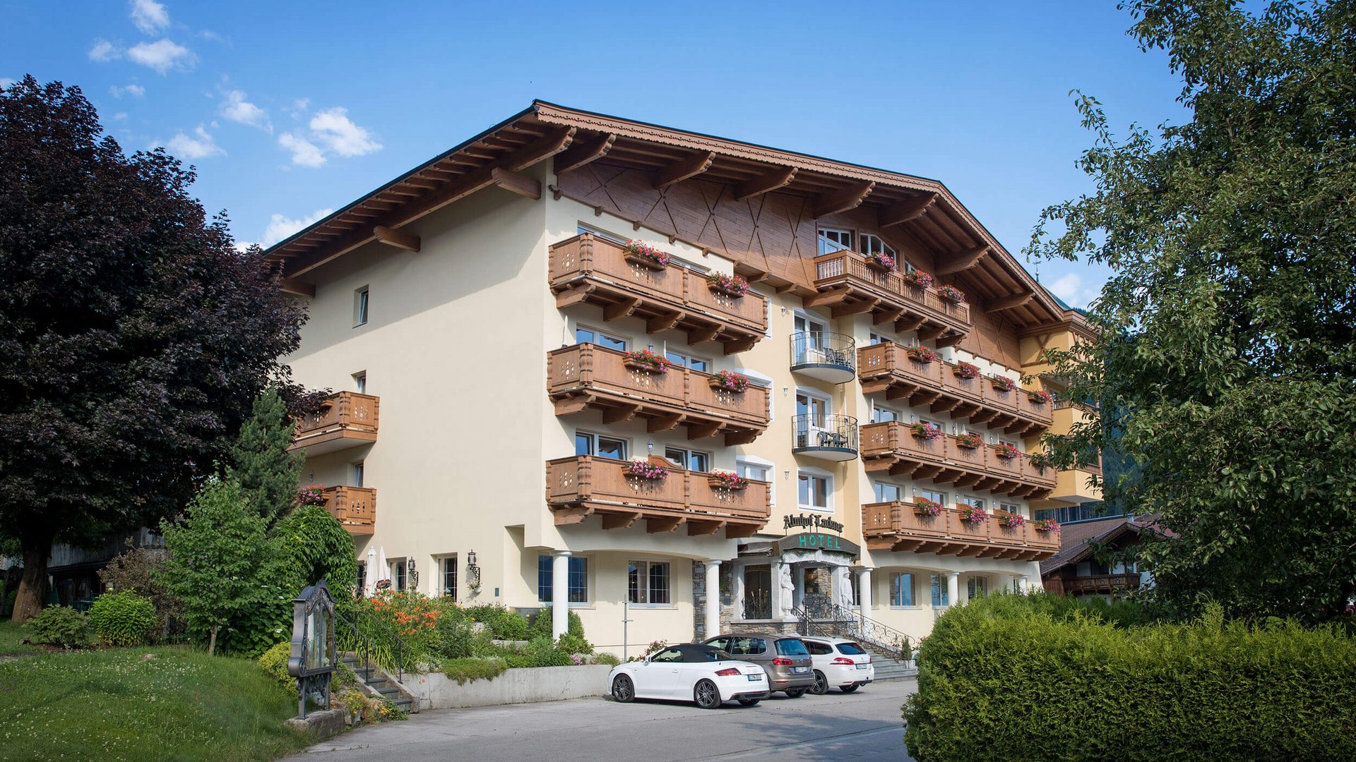 Hotel mit Holzbalkonien und Parkplätzen bei klarem Himmel