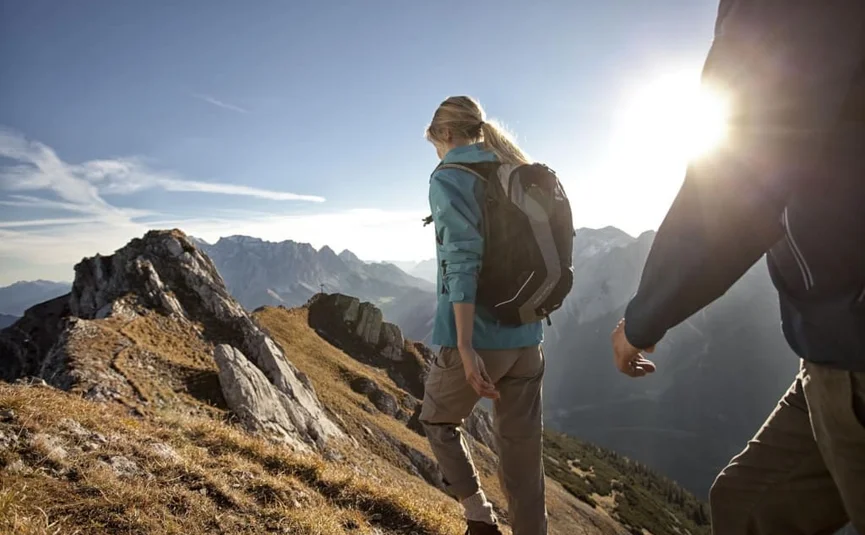 Twee wandelaars met rugzakken wandelen op een zonnig bergpad