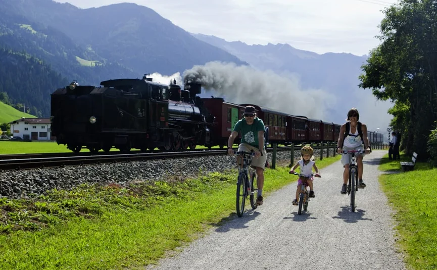 Bike week Family cycling beside a steam locomotive on a countryside path