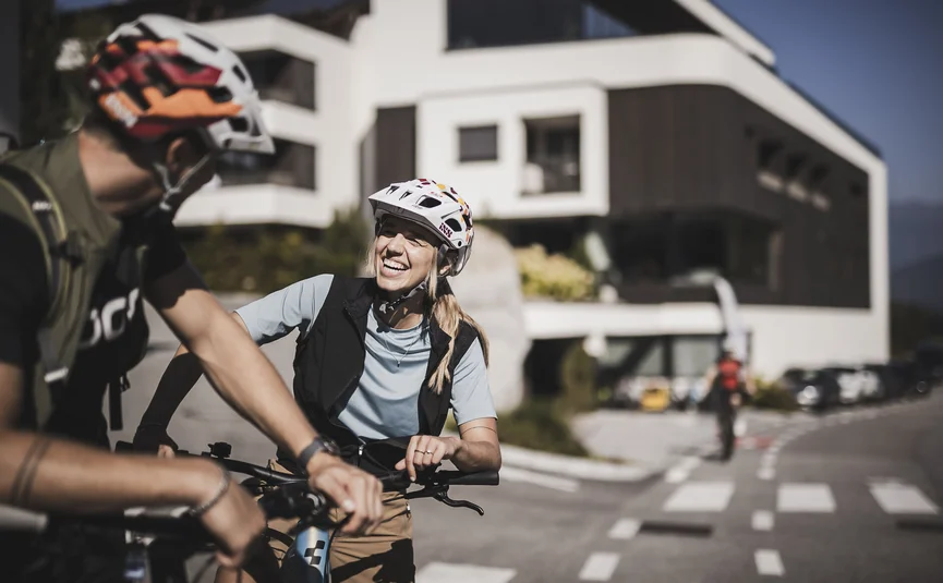 Woman and man wearing bike helmets smiling outside on a sunny day