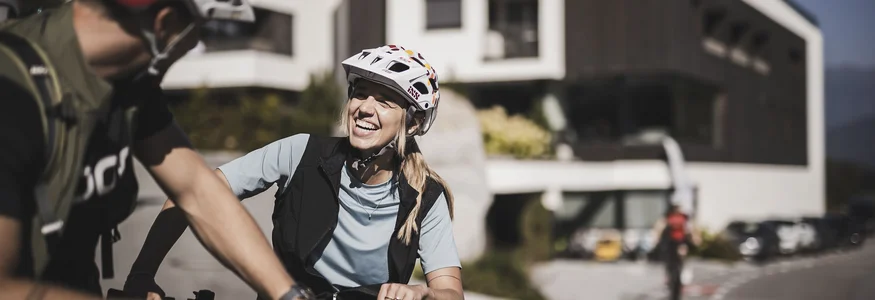 Ein perfekter Enduro-Tag – vom ersten Höhenmeter bis zum letzten Trail © Kottersteger Frau und Mann mit Fahrradhelmen lachen draußen an einem sonnigen Tag